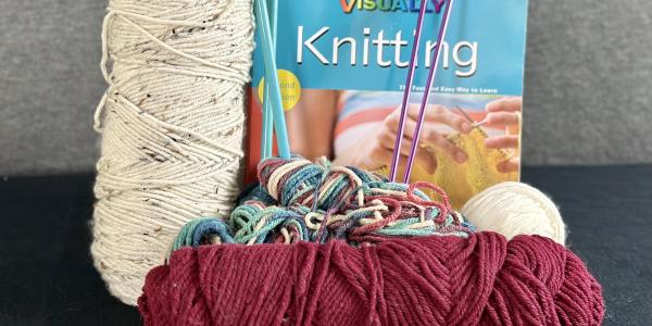 Assorted yarn, needles, and a knitting book