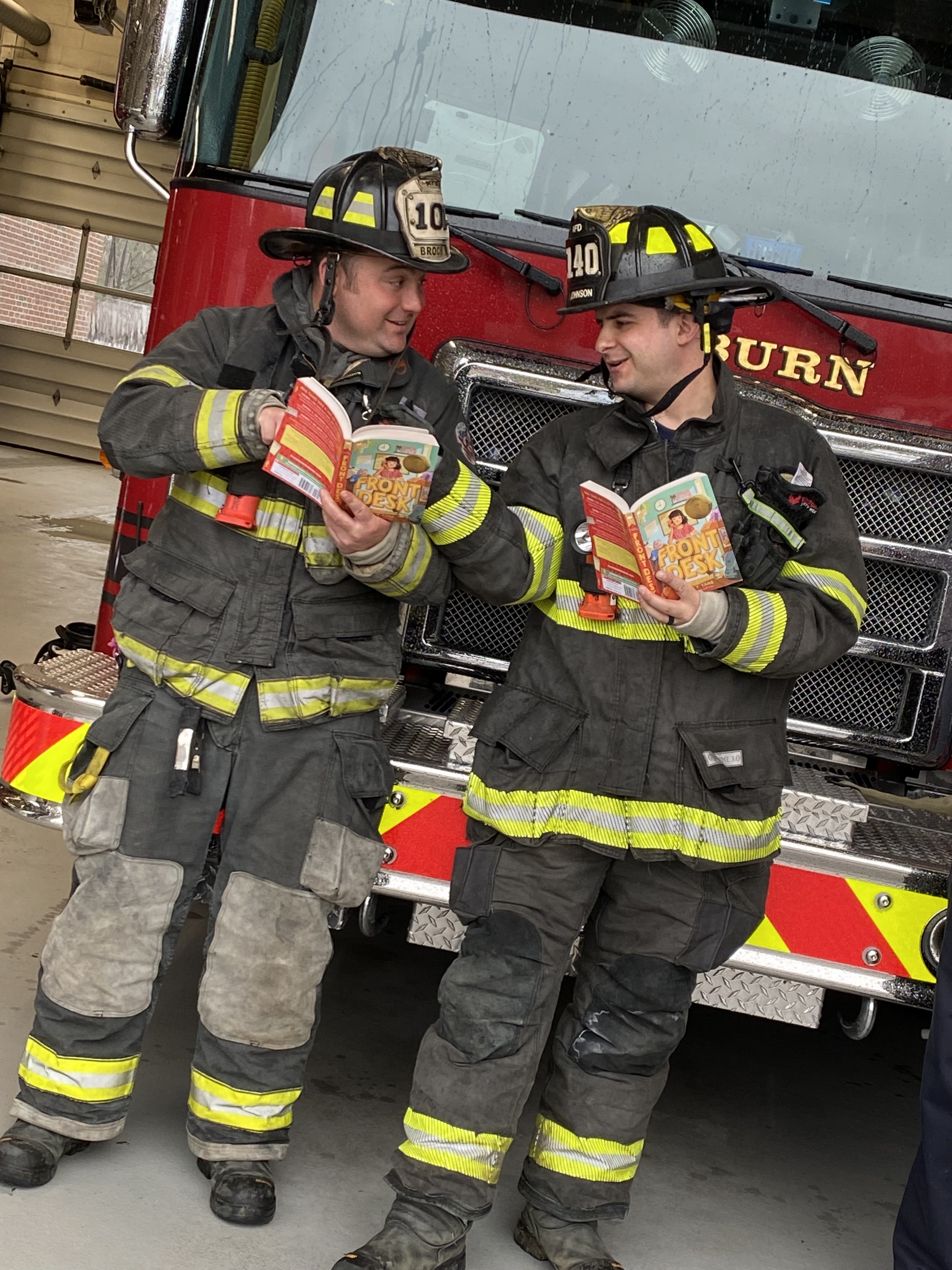 Fire fighters reading in front of fire engine. 