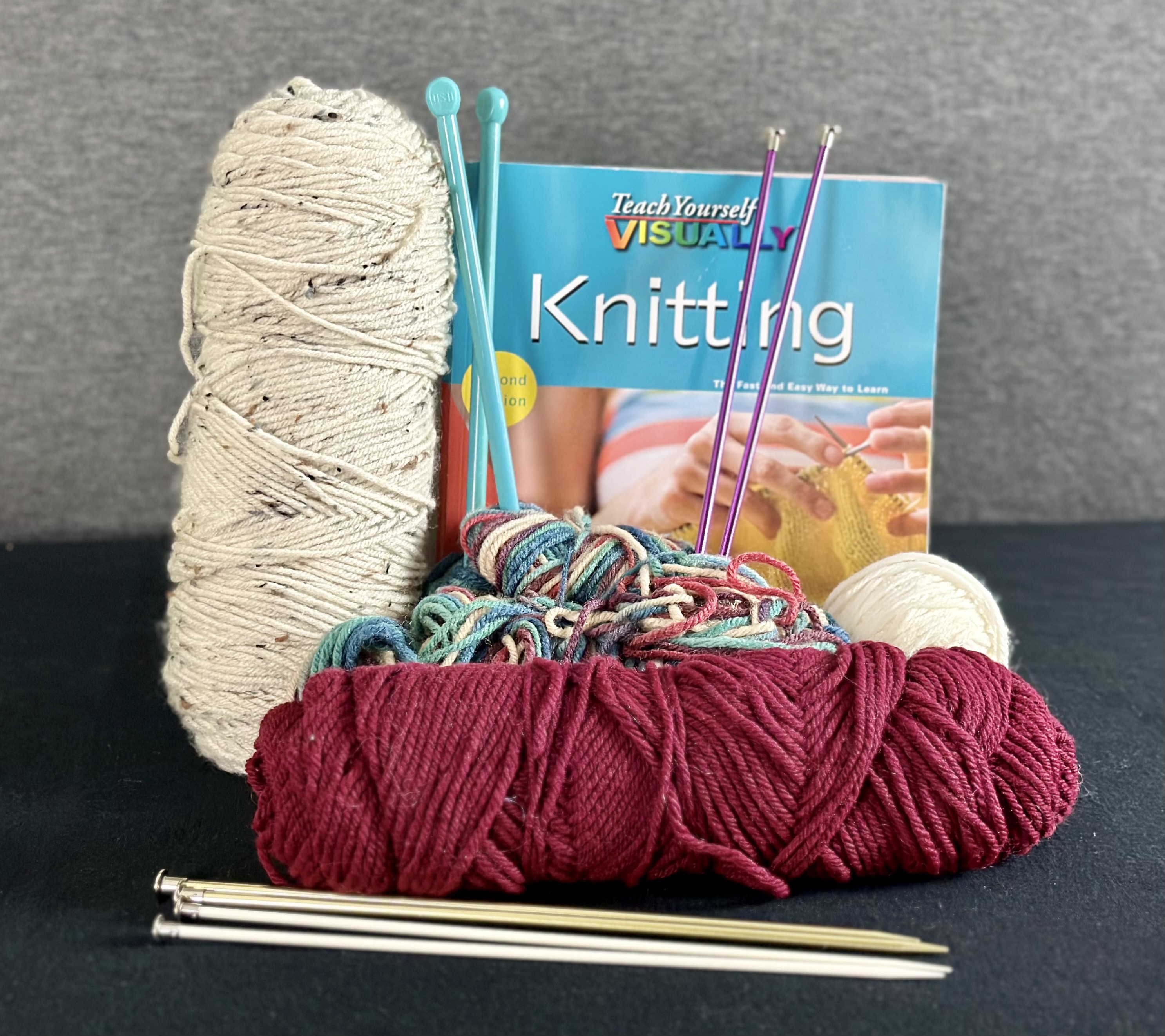 Assorted yarn, needles, and a knitting book