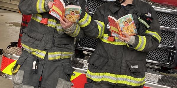 Fire fighters reading in front of fire engine. 